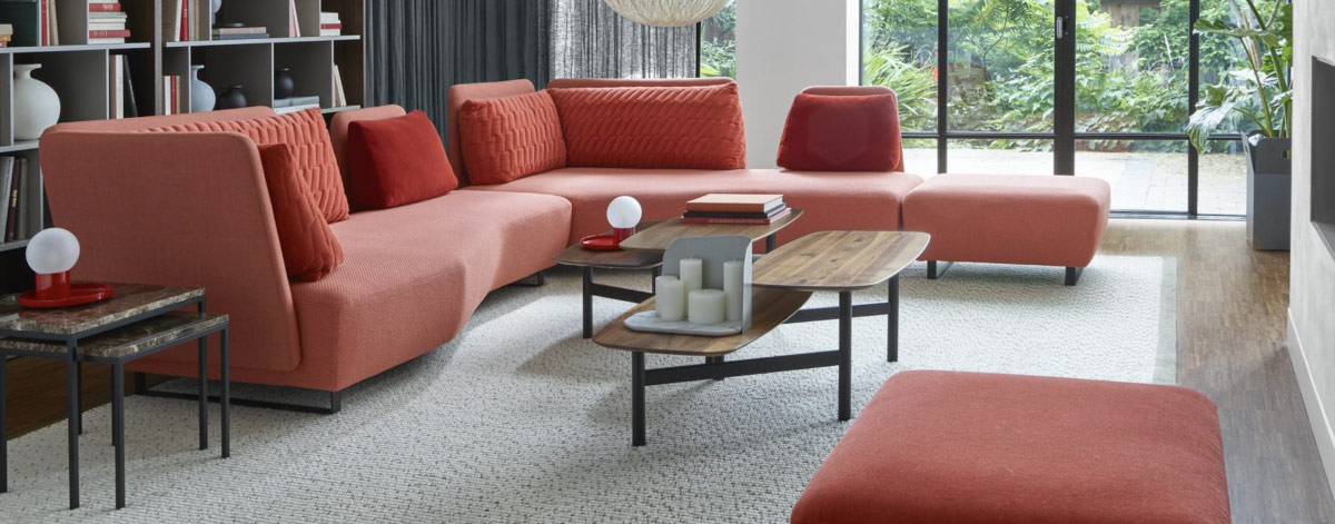 Sofa w kształcie fortepianu, nieregularnych wysokości oparcia, różnych kształtów i wielkości poduszki.